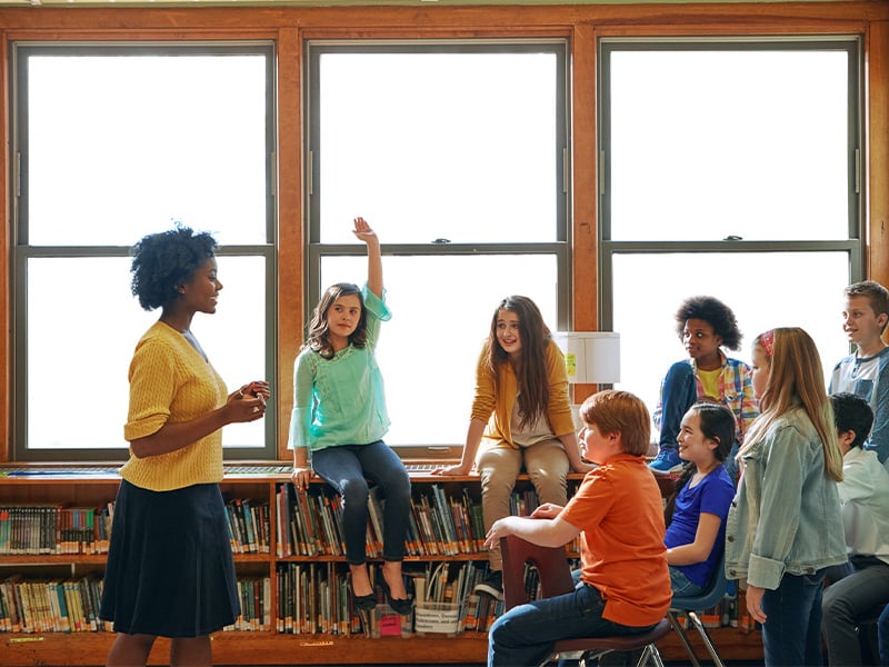 teacher-lecturing-class-around-bookshelf-4-3