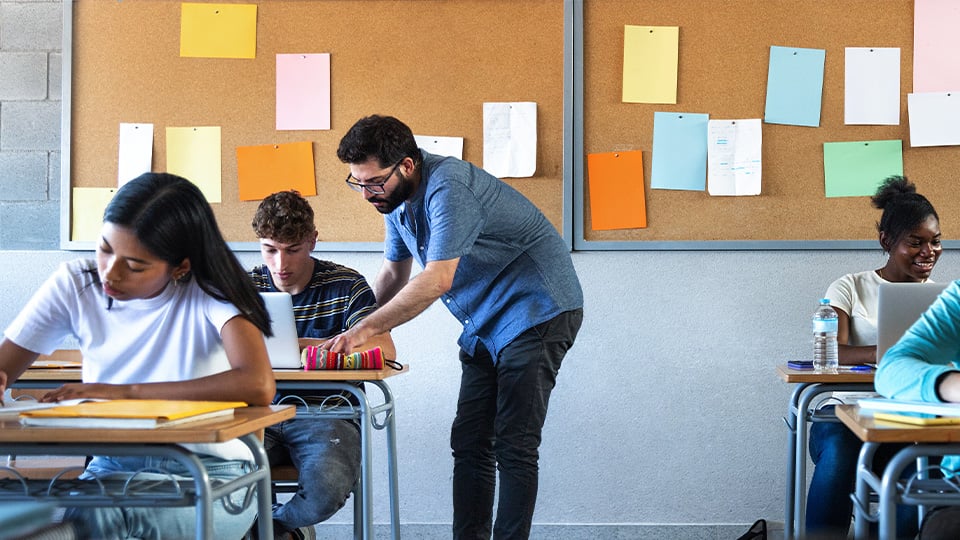 teacher-helps-student-on-laptop